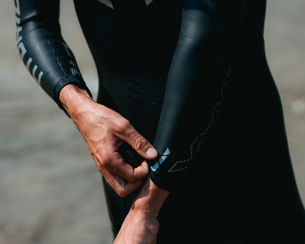 Close-up of an athlete adjusting the wrist cuff on a Synergy wetsuit
